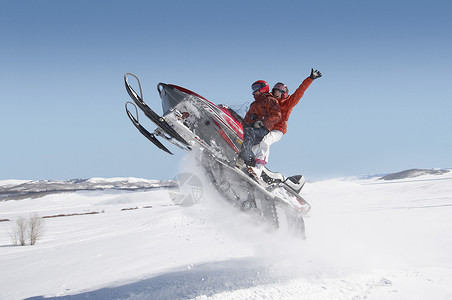 一对夫妇在雪中跳雪车的侧边视图伙计们活动热情双手摩托活力加速度速度手臂男人背景图片