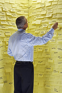 一名商务人士站在墙前 贴着粘黏纸条的一面后视线压力职业沉思人士成人管理人员商务房间正装背诵背景图片