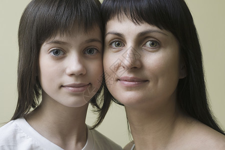 母亲和女儿微笑的演播室肖像裁剪个人视图长发特写女孩头肩头发家长女性背景图片