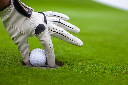 男人的手把高尔夫球打进绿地洞游戏裁剪手套运动闲暇优胜者俱乐部男性课程手指背景图片