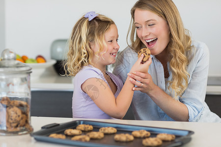 吃饼干的女孩女孩在柜台给母亲喂饼干背景