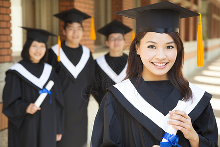 毕业季节素材拥有同学毕业文凭的漂亮美丽的大学毕业生和同班同学背景