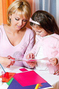 母亲和女儿从一张彩纸上剪掉数字艺术家庭团体女士游戏室幼儿园黏土孩子艺术家童年红色的高清图片素材