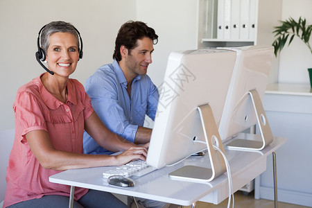 使用计算机在办公桌与妇女使用耳机的妇女一起工作的临时商业小组商务同事职员沟通生意人呼叫操作员职场技术合伙呼叫中心高清图片素材
