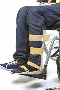 为坐在轮椅上的青年男子提供矫形设备     封闭鞋高清图片素材
