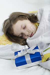 小女孩睡在有礼物的床上做梦高清图片素材
