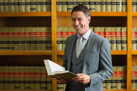 律师在法律图书馆持有书籍男人架子大学书架男性学习体积知识学校微笑背景图片