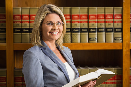 律师在法律图书馆阅读书教科书女性阅读高等教育金发女郎书架微笑法律图书馆学校背景图片
