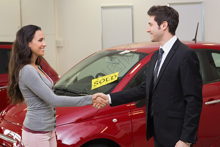 人在一辆被卖车前面握手汽车微笑零售女性男性营业员运输钥匙女士职业背景图片