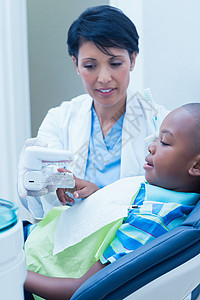 显示男孩假肢牙齿的牙医口腔科牙科黑色女性病人诊所女士考试保健工作背景图片