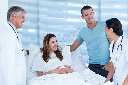 未来父母与笑着的医生交谈器材关爱药品专家康复从业者说谎孕妇装医院保健背景图片