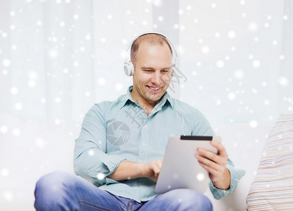 坐在沙发上笑着的平板电脑的人时间男性房间互联网自由职业者工具男人音乐技术药片游戏高清图片素材