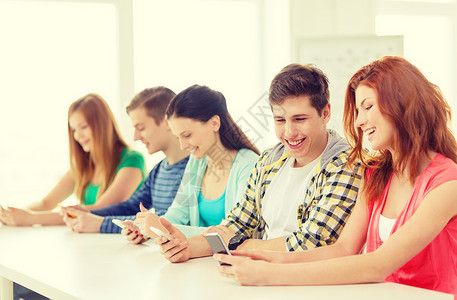 青少年演讲学校里带智能手机 微笑着微笑的学生团队社会同学朋友们图书馆课堂女孩互联网视频男生背景