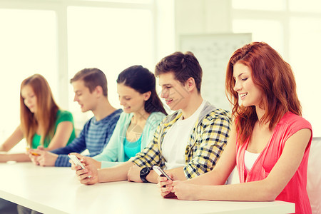 学校里带智能手机 微笑着微笑的学生青少年团体社会大学班级互联网男生同学团队技术背景图片