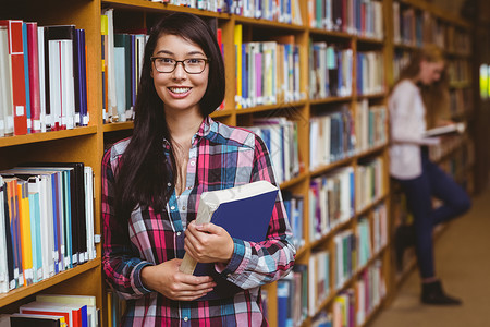 微笑的学生靠在书架的书架上女孩高清图片素材