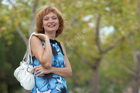 青年女子在秋季公园中行走叶子眼睛微笑金发女郎森林喜悦快乐阳光幸福头发金的高清图片素材