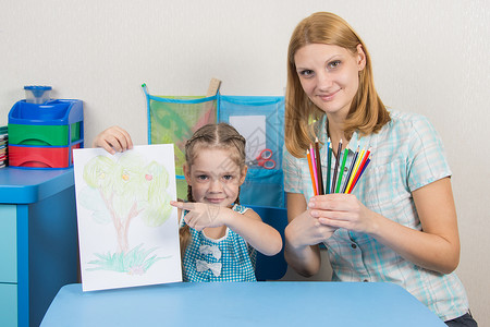 5岁女孩在照片上展示 我母亲一直握着彩色铅笔的手轮流高清图片素材