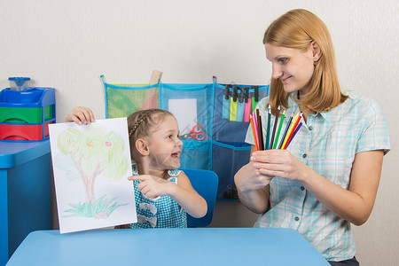 5岁女孩在照片上展示 并看着我母亲 她握着有色铅笔的手出去高清图片素材