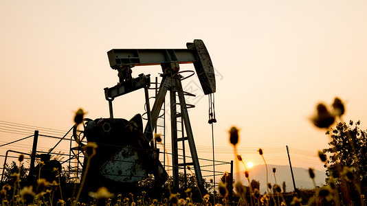 在一个石油钻井工地的劫油机技术力量原油管道气体化石场地燃料天空太阳背景图片