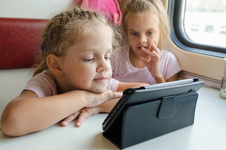 两个女孩在火车上 有兴趣看卡通牌电脑的女孩背景图片
