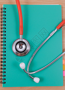 医疗分析手册红色听诊器躺在薄绿色书上医生乐器办公室知识职业蓝色考试文档记录诊断背景