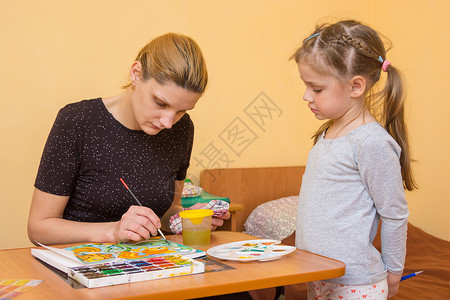 厚涂插画小女孩看着画家在桌边的纸上涂水彩色背景