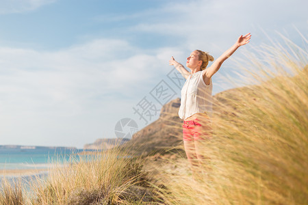 自由快乐的女子在节日中享受阳光头发假期海滩女性喜悦幸福女孩太阳生活冥想云高清图片素材