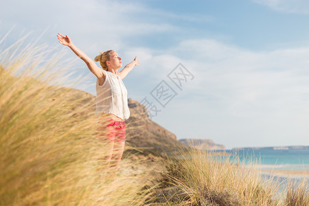 自由快乐的女子在节日中享受阳光天空冥想喜悦生活女孩女性幸福海滩头发旅行户外的高清图片素材