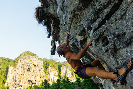 和快乐的强壮男人攀登高岩 在海面上与小屋冒险高清图片素材