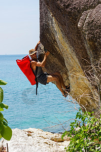 一个坚强而快乐的人 带着小屋和红色的海袋在海上攀登高高的岩石登山者天空旅行男人运动员登山运动力量顶峰勇气脸高清图片素材