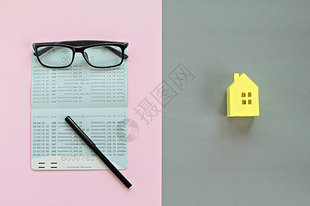 储蓄账户活纸簿 笔 粉红背景眼镜和灰色背景黄纸店的银面纸袋金融的高清图片素材