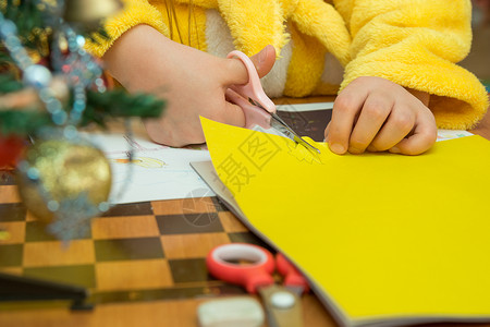 剪纸圣诞树孩子从建筑纸上切掉一个明星 准备圣诞手工艺品 特写背景