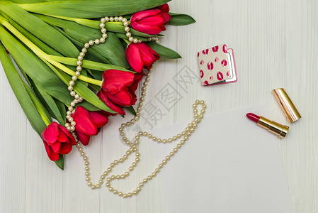 白红色郁金香白木板上的红色郁金香花束床单口红问候语笔记项链婚礼叶子地面木材背景
