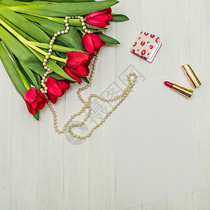 白木板上的红色郁金香叶子木材正方形问候语木头庆典口红笔记花束婚礼背景图片