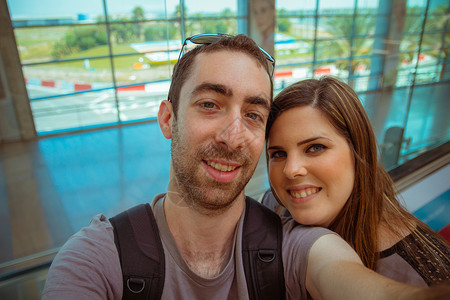 快乐的一对夫妇在机场用智能手机或相机自拍游客女孩享受魅力画像旅行闲暇蜜月微笑乐趣背景图片