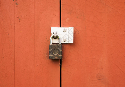 红色的墙一个金属挂锁保护锁定外面的两扇木门背景