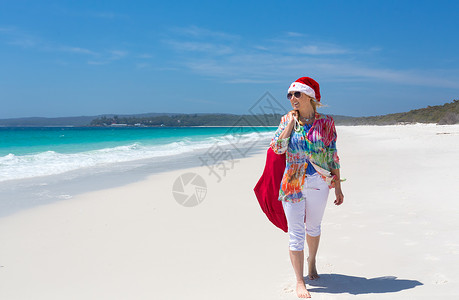 朴实无华圣诞节在沙滩上 夏日阳光下 女性与圣塔一起散步背景