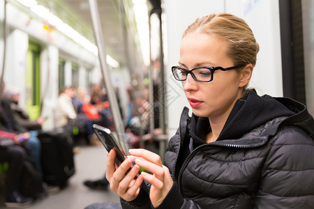 普通火车年轻女孩在地铁的手机屏幕上阅读旅行民众铁路火车社会商业城市游客通勤者电话背景