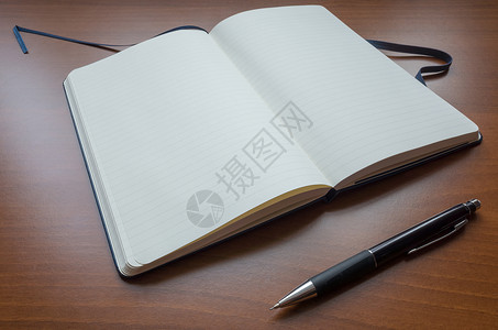 打开笔记本白纸笔记本和棕色木制表背景的薄纸背景