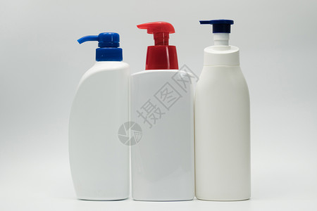 三瓶装有红色和蓝色泵的白色酒瓶高清图片