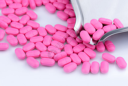 mg动效在不锈钢药物托盘附近的白色背景上的一堆粉红色药丸 诺氟沙星 400 mg 用于治疗膀胱炎 抗生素耐药性 抗菌药物使用要有合理的观背景