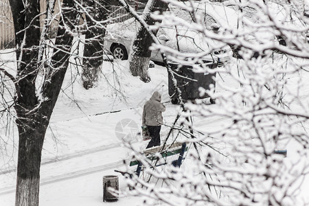 一个路过者在大雪中穿过寒雪的市区院子气候男人薄片降雪假期场景血统女孩男性风暴背景图片