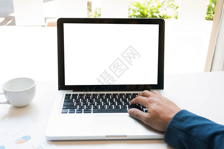 一个男人用笔记本电脑在木制桌子上工作设计师高清图片素材