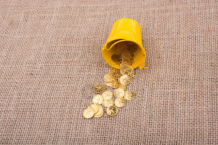 帆布上装着罐子和假金硬币现金经济金融概念财富银行业宝藏商业金子金币背景图片