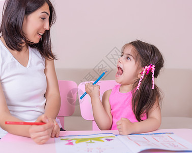 看图画书女孩母亲和女儿用纸上铅笔学习活动手册女孩妈妈幼儿园老师测试火车桌子苗圃快乐蜡笔背景