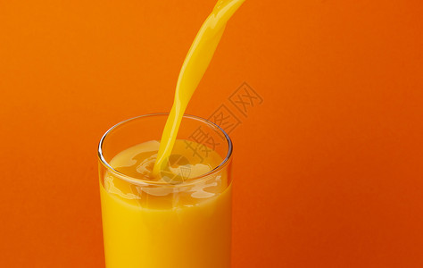 橙汁倒入玻璃杯中 隔绝在彩色背景上 有复制空间高清图片