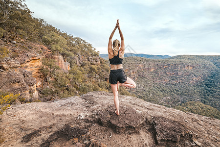 女性强度和瑜伽平衡的亚萨纳山悬崖壁背景图片