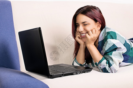 年轻女孩在床上用笔记本电脑聊天年轻的高清图片素材