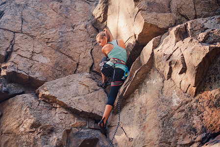 美丽的女人爬上山中的岩石 冒险和极限运动概念勇气女孩首脑探索天空日落女性登山者风险绳索成功高清图片素材