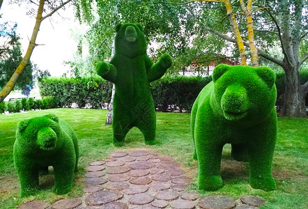 雕塑制作从树底的人工草地上 雕刻出三只熊背景